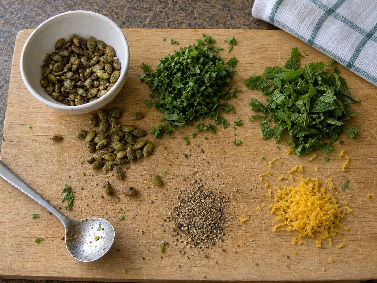 Pumpkin seeds, chopped herbs, lemon zest, and pepper for finishing couscous roasted vegetable salad.