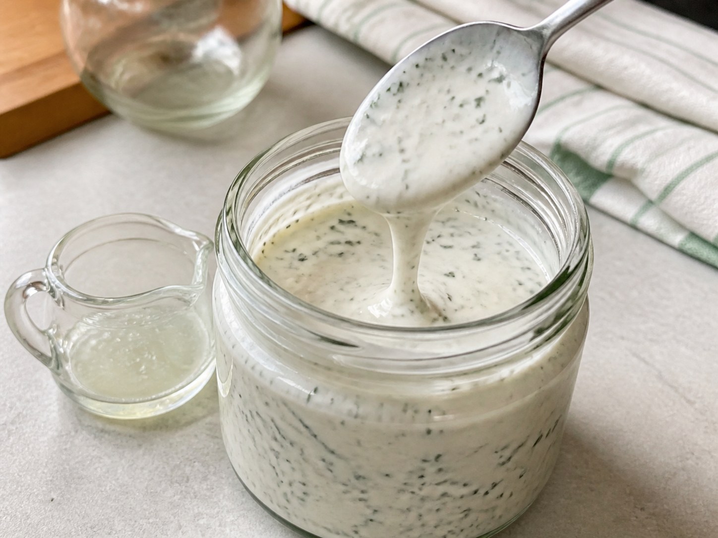 Greek yogurt ranch being thinned to a creamy drizzleable texture.