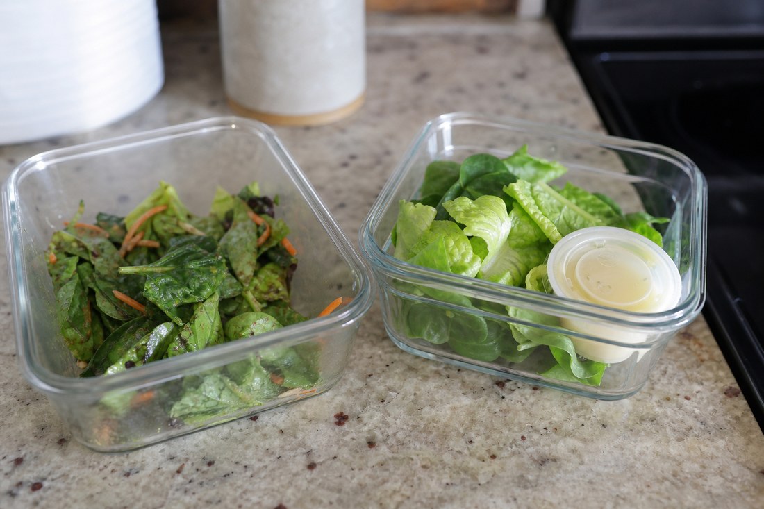 Two small salad containers showing an early-dressed tender salad beside a fresher dry salad with a dressing cup.