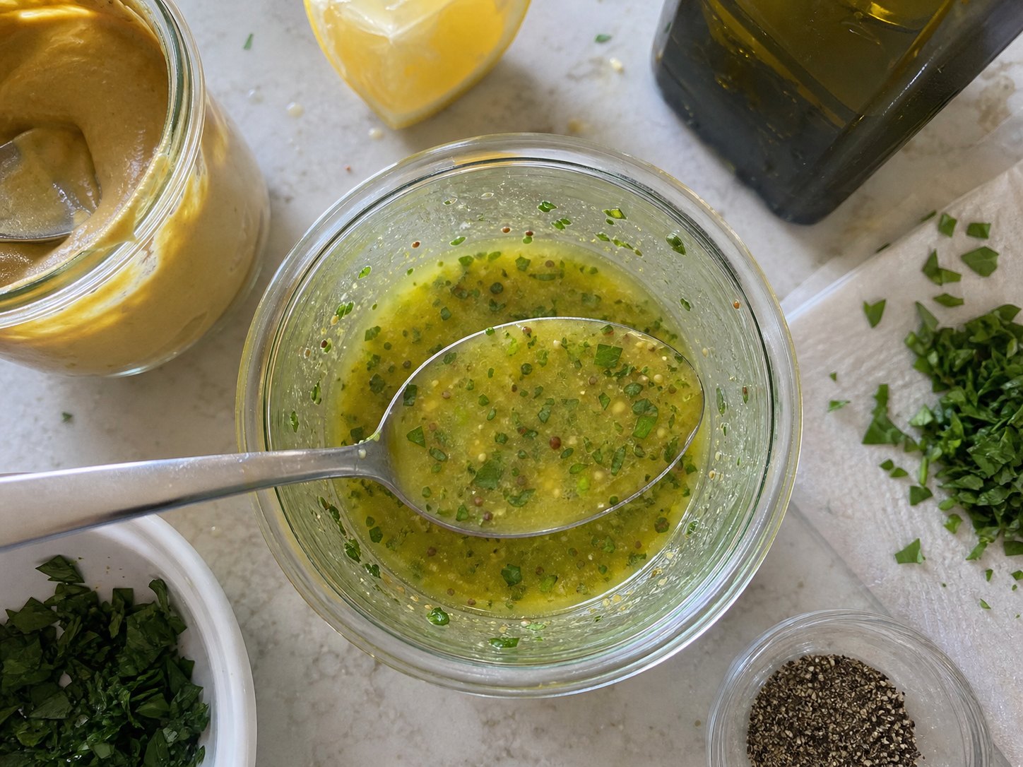 Mustard herb dressing in a small cup with herbs and lemon for egg and chickpea protein salad.