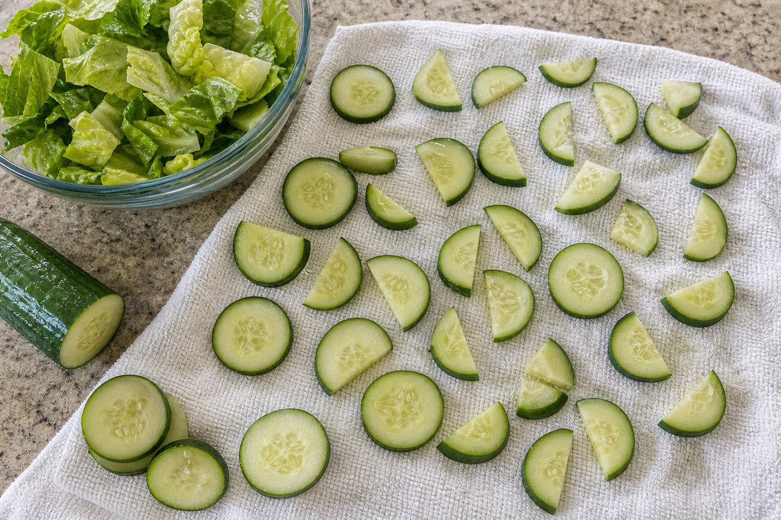Cucumber slices spread on a towel before packing a chicken cucumber salad.