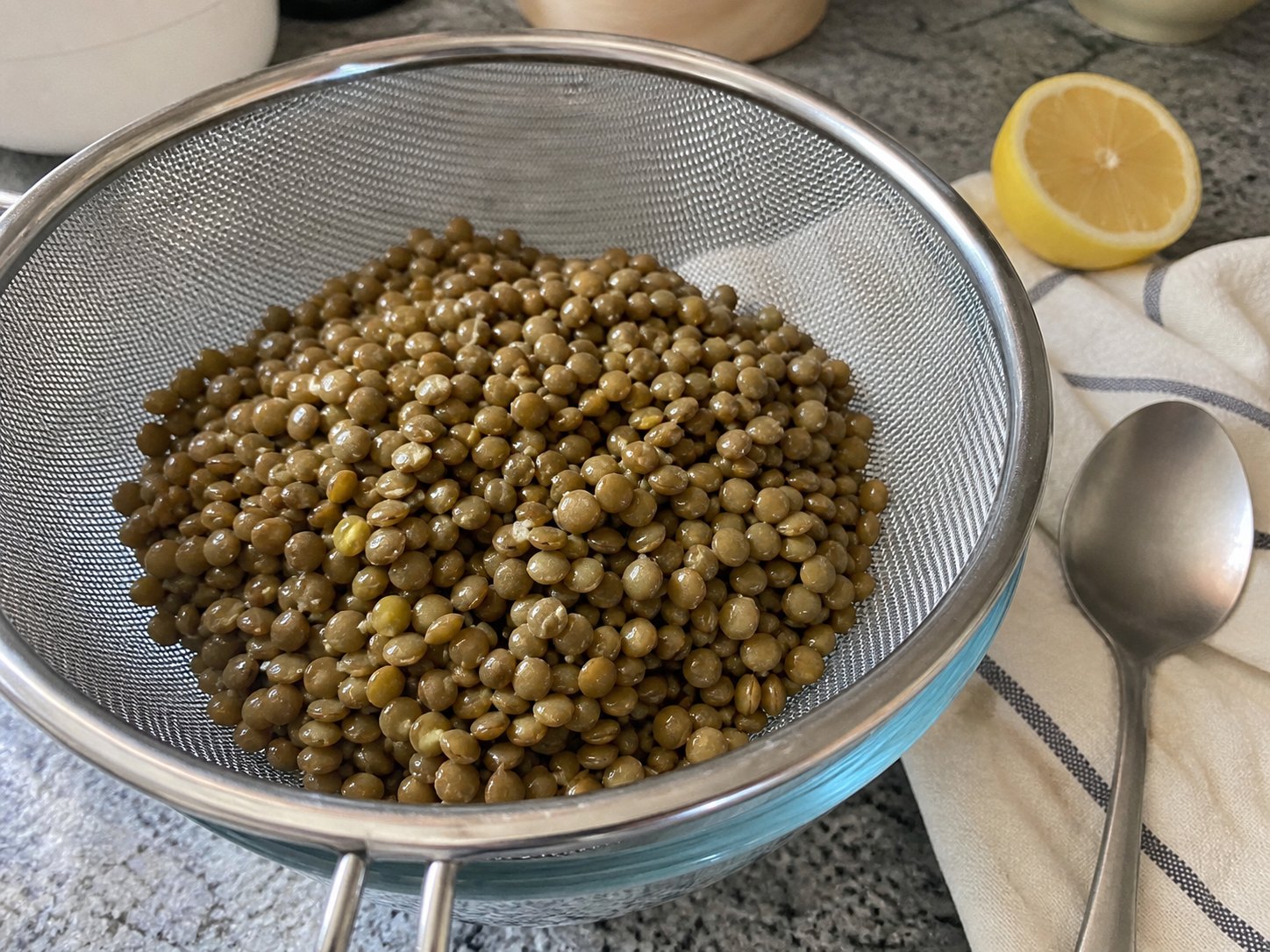 Cooked green lentils draining in a strainer before lentil lemon Dijon salad.