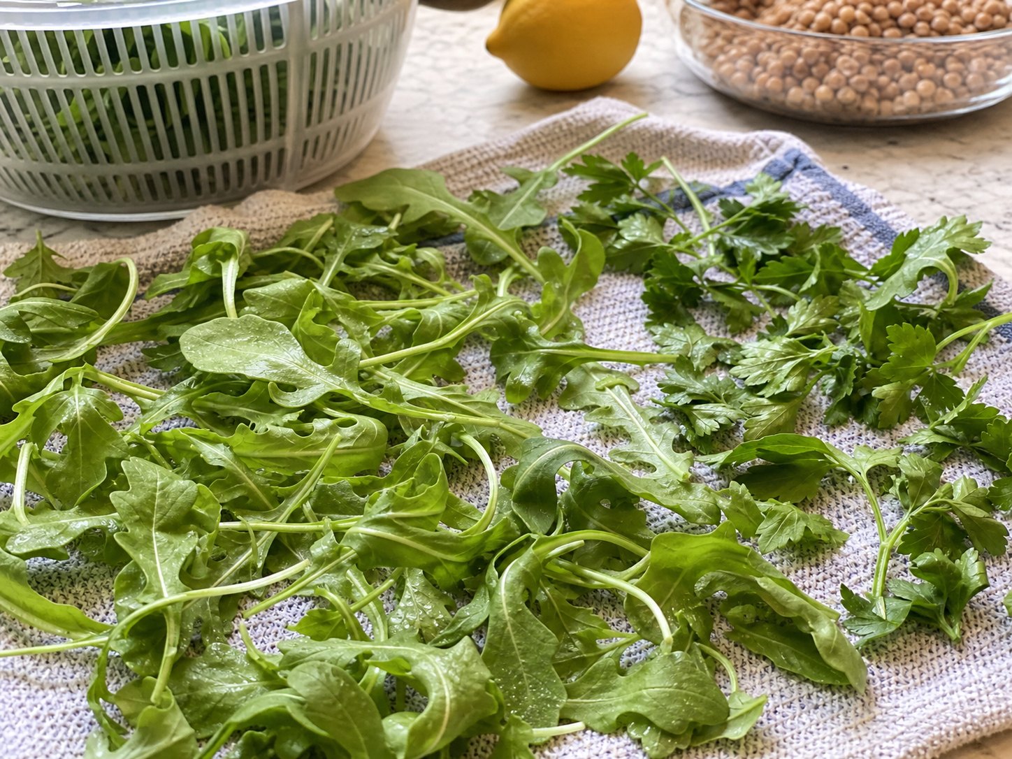 Arugula and parsley drying on a towel before packing lentil lemon Dijon salad.