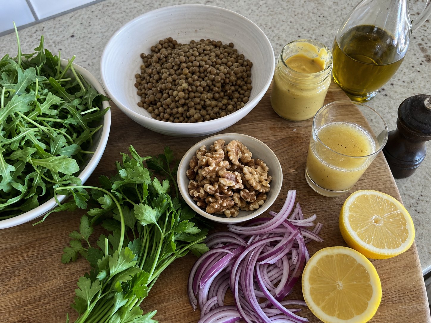 Lentil lemon Dijon salad ingredients with cooked lentils, arugula, parsley, red onion, walnuts, lemon, Dijon mustard, olive oil, and dressing.