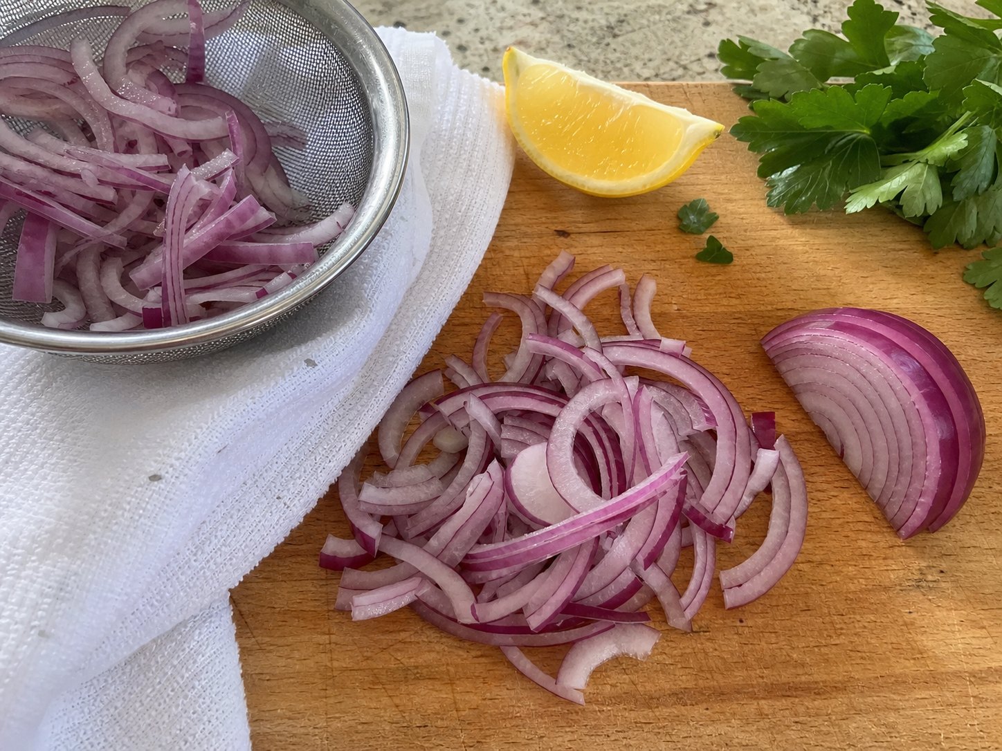 Thin red onion slices draining on a towel before lentil lemon Dijon salad.
