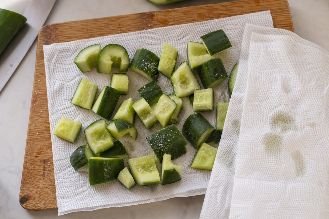 Chopped cucumber pieces on a towel for Mediterranean chickpea salad meal prep.