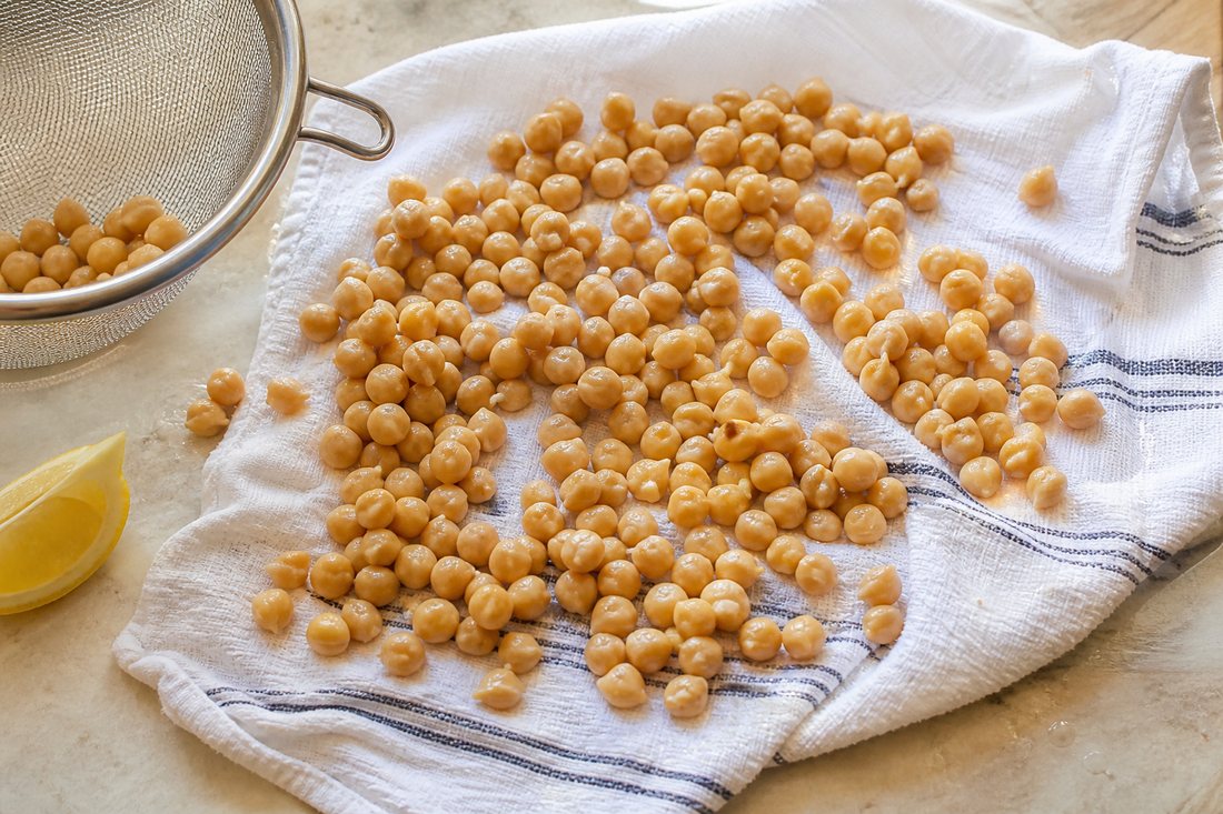 Rinsed chickpeas spread on a kitchen towel to dry before Mediterranean chickpea meal prep salad.