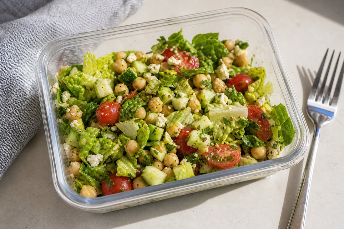 Mediterranean chickpea meal prep salad after lunch mixing with romaine, chickpeas, cucumber, tomatoes, feta, herbs, and light vinaigrette.