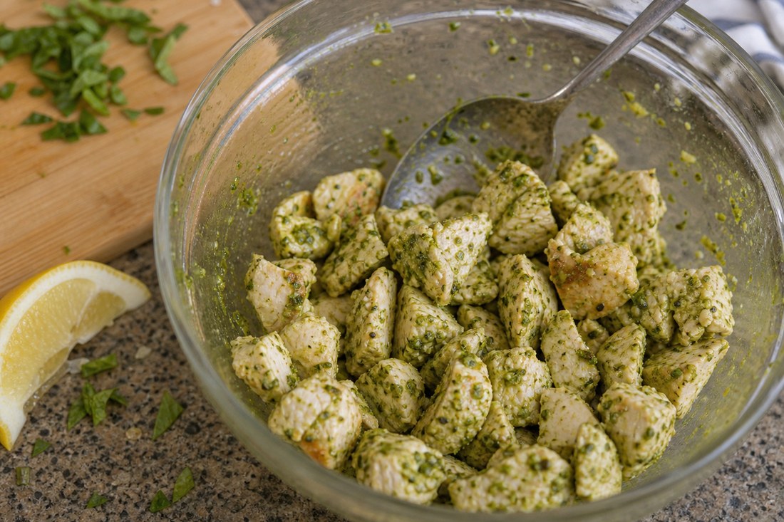 Cooked chicken pieces lightly coated with basil pesto for chopped salad.