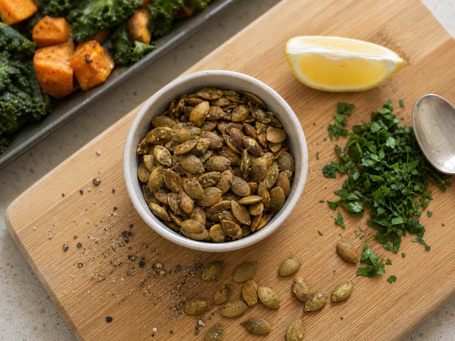 Pumpkin seeds, herbs, lemon, and pepper for finishing roasted sweet potato kale salad.