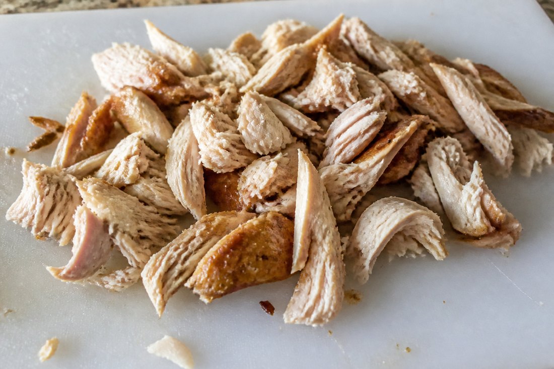 Rotisserie chicken pulled into irregular pieces for salad.