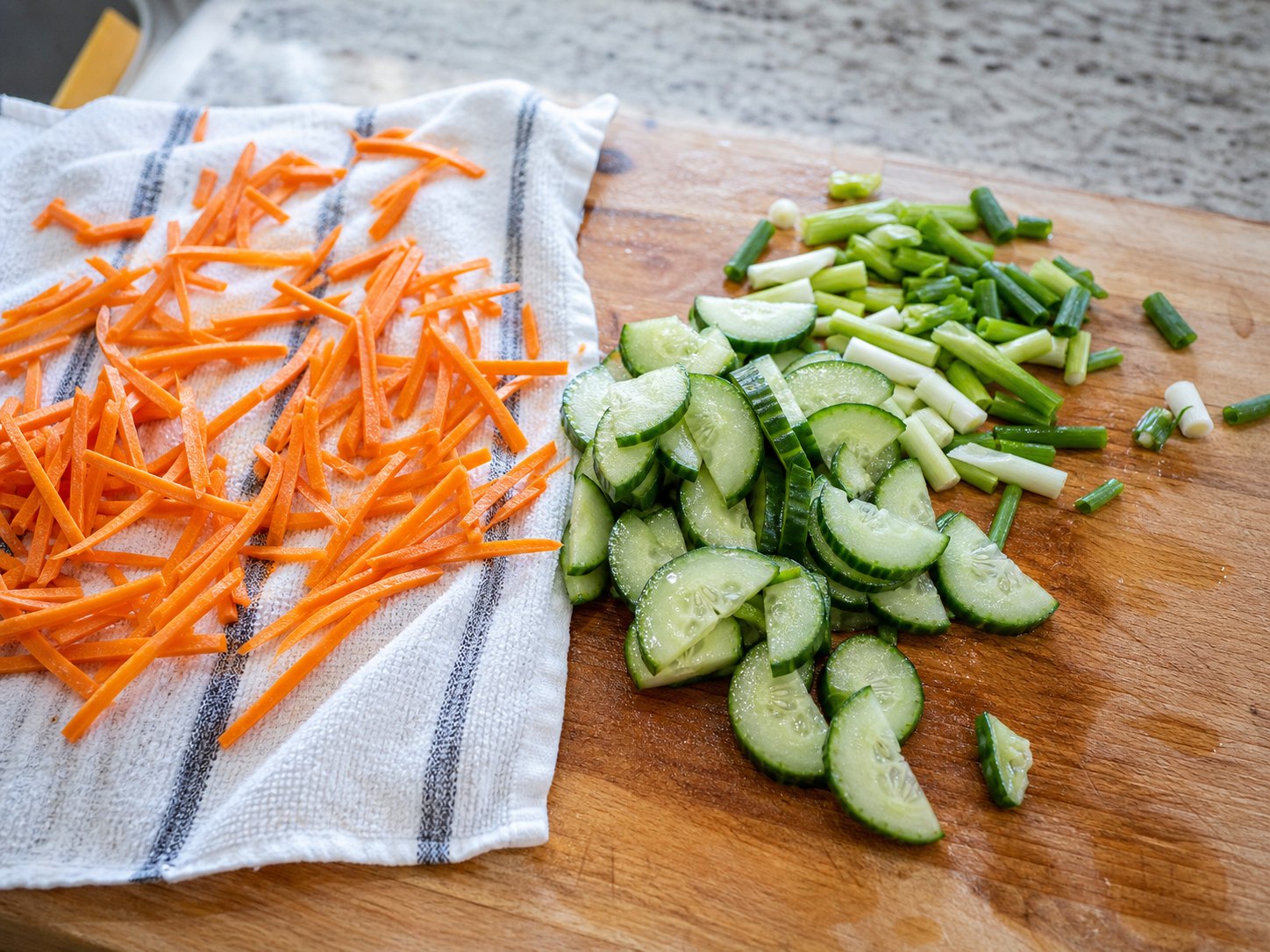 Carrot matchsticks and cucumber slices drying before sesame tofu cabbage salad.