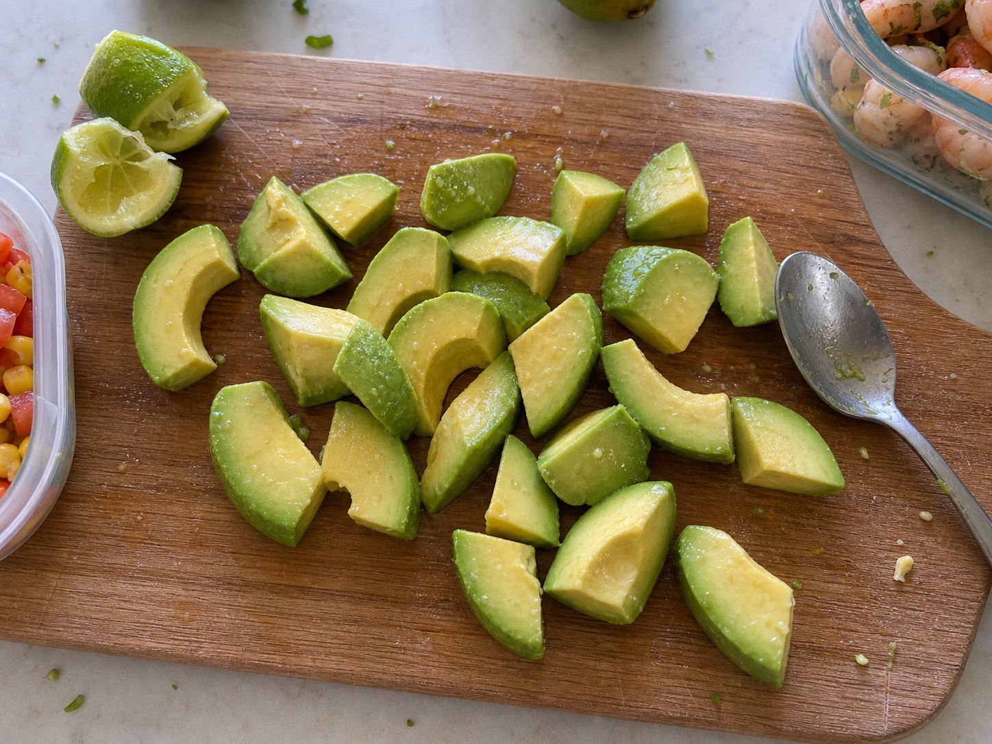 Avocado chunks with lime on a cutting board for shrimp avocado corn tomato salad.