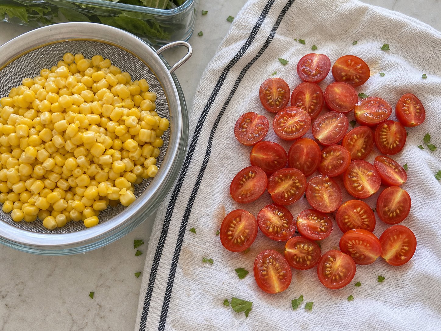 Corn kernels and halved cherry tomatoes draining on a towel before shrimp avocado salad.