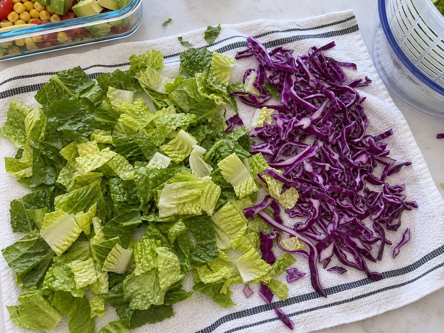 Chopped romaine and shredded purple cabbage drying on a towel for shrimp avocado salad.