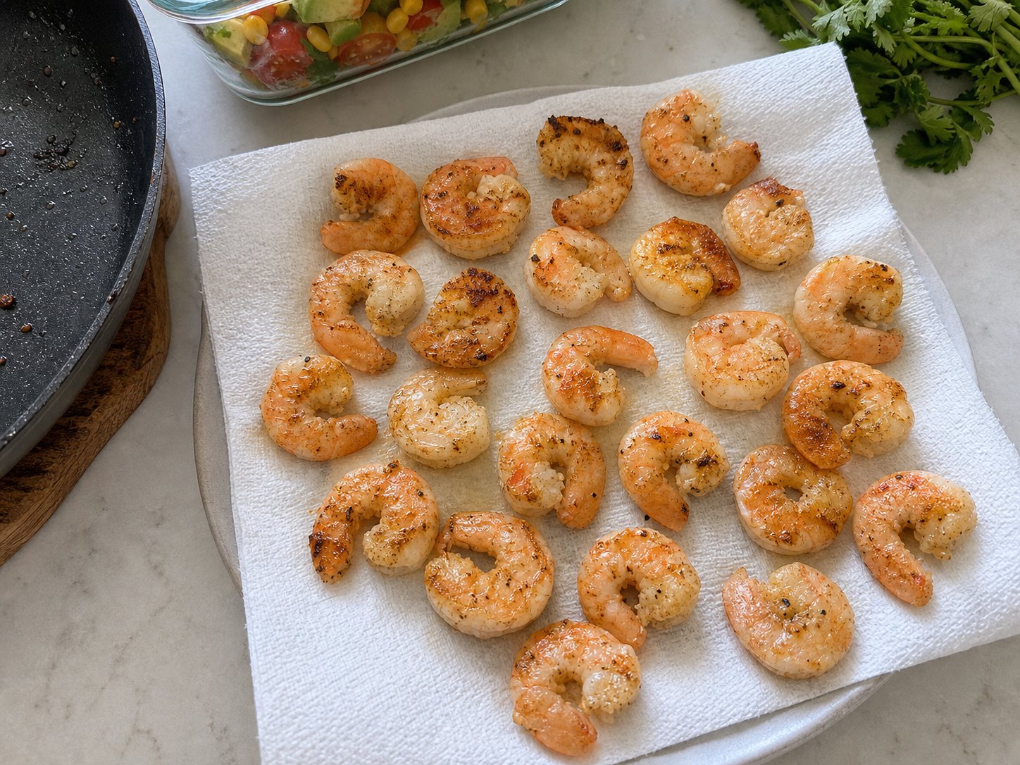 Seared shrimp cooling on a towel before packing shrimp avocado corn tomato salad.