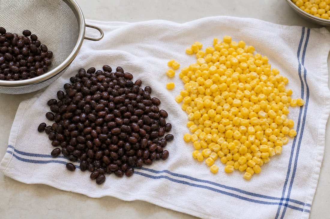 Drained black beans and corn on a towel before Southwest chicken salad jar assembly.