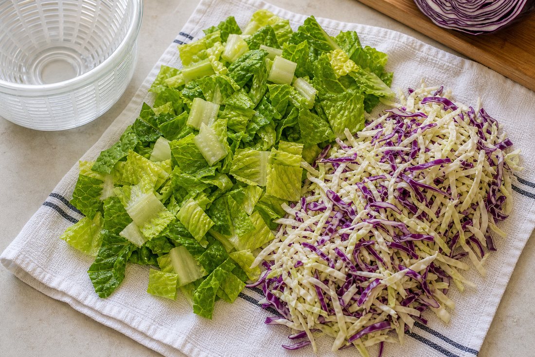 Dry chopped romaine and shredded cabbage on a towel for Southwest chicken salad jars.