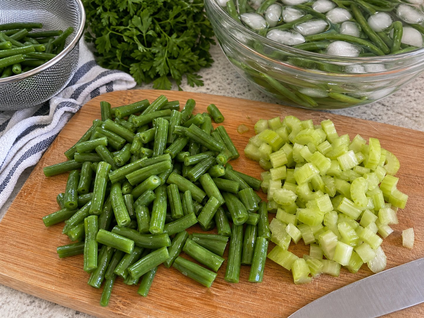 Cooked green beans and chopped celery prepared for three-bean picnic salad.