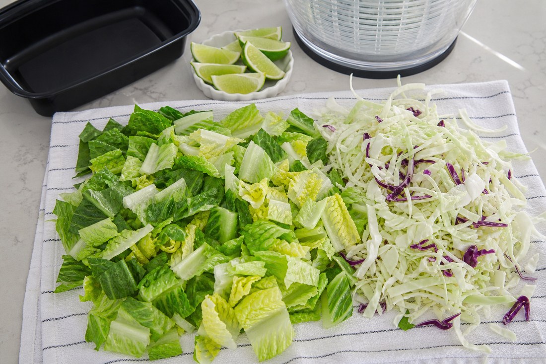 Dry chopped romaine and shredded cabbage on a towel for turkey taco meal prep salad.